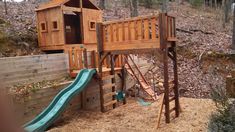 a wooden play set in the woods with a slide