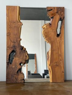 a mirror that is sitting on top of a wooden table next to a white wall