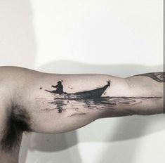 a man with a tattoo on his arm is rowing a boat in the water while wearing a hat