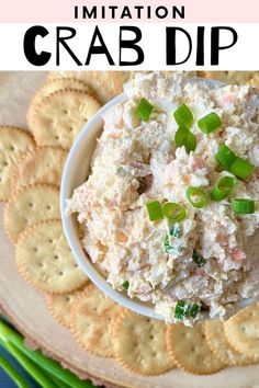 crab dip in a white bowl with crackers on the side and green onions garnish