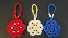 three small crocheted ornaments are shown on a black surface, one is red, one is blue and the other is yellow