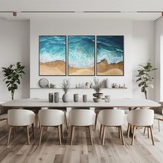 a dining room table with four chairs and two paintings on the wall above it that have waves coming in from the ocean