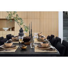 a dining table set with black chairs and plates