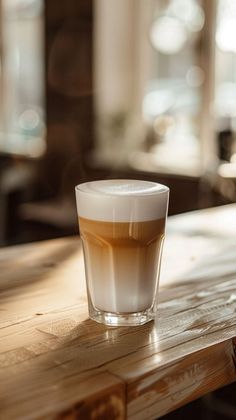 a glass filled with liquid sitting on top of a wooden table