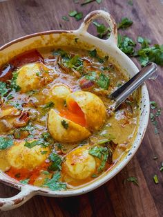 a bowl filled with some kind of food on top of a wooden table and garnished with cilantro