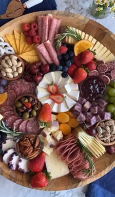 a wooden platter filled with different types of cheese and meats