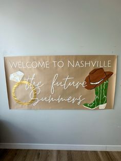 a welcome sign is hanging on the wall next to a wooden floor and white walls