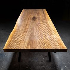 a wooden table sitting on top of a cement floor next to a black wall in a dark room