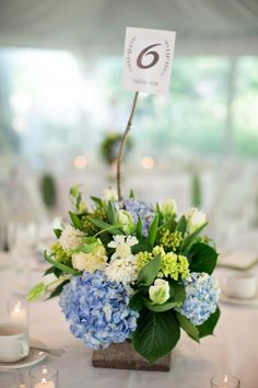 there is a vase with blue and white flowers in it on top of the table