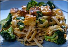 a plate with noodles, broccoli and tofu