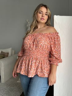 The fun and flattering Plus Size Elasticized Floral Blouse is a great addition to any warm-weather outfit collection. This plus size top is great worn with a cute pair of trending jeans for an effortless look or dress it up a bit with some statement pants. This blouse features an elasticized top hemline that can be worn on or off the shoulder, a decorative tie on the bust, and elastic around the waistline and at the ends of the 3/4 length sleeves. The material is a non-stretchy woven. This top i Orange Relaxed Fit Blouse For Vacation, Peach Feminine Blouse For Day Out, Feminine Peach Blouse For Day Out, Peach Blouse For Spring Beach Occasions, Peach Blouse For Beach In Spring, Peach Blouse For Beach, Spring Season, Orange Floral Print Relaxed Fit Blouse, Orange Relaxed Fit Blouse With Floral Print, Relaxed Fit Orange Blouse With Floral Print