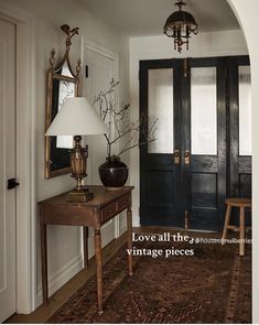 an entry way with two black doors and a lamp