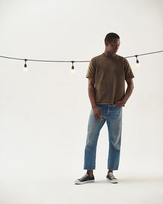 a man standing in front of a string with lights hanging from it's sides