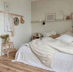 a bedroom with white linens and wooden floors