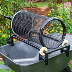 a large grill sitting on top of a grass covered ground next to flowers and bushes