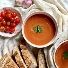 two bowls of tomato soup, bread and cherry tomatoes