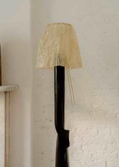 a lamp that is on top of a table next to a white brick wall and floor