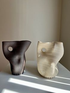 two vases sitting on top of a table next to each other