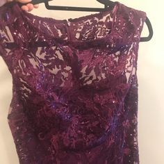 a purple dress hanging on a hanger with someone's hand holding it up