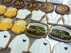 decorated cookies are arranged on a table with numbers and beer mugs in the shape of shirts