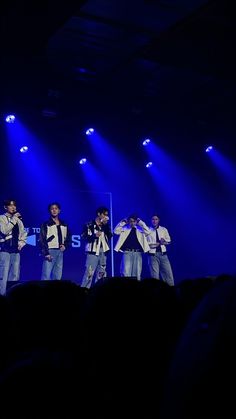 four men standing on stage in front of blue lights