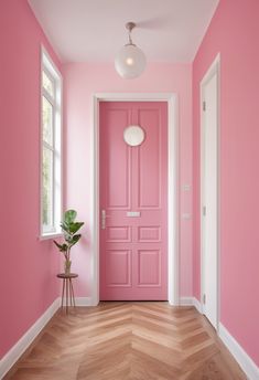 a pink door in a room with wood flooring and white trim on the walls