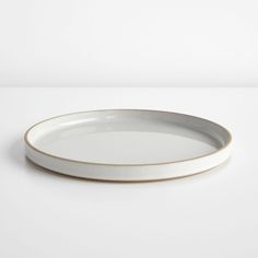 a white and gold plate sitting on top of a table next to a white wall