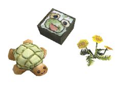 a stuffed turtle next to a flower and a small box with an angry face on it