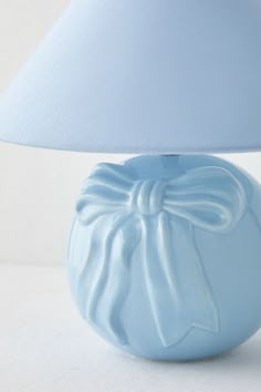 a blue vase with a bow on it and a white lamp in the corner behind it