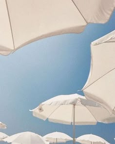 many white umbrellas are lined up against the blue sky