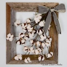 a wooden frame with cotton flowers and a bow