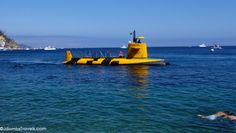 a yellow submarine floating on top of the ocean next to a man swimming in it