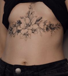 a close up of a woman's stomach with flowers tattooed on the side and behind her