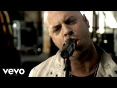 a man singing into a microphone while standing in front of a guitar and wearing a leather jacket