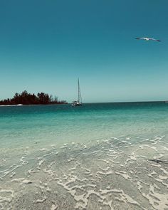 the water is crystal blue and clear with small boats in the distance on the horizon