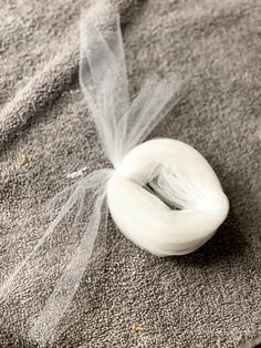 a spool of white thread sitting on top of a piece of gray fabric next to a tulle