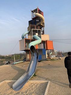 a man walking past a slide in the sand