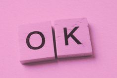 the word ok spelled with black ink on pink paper