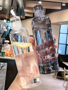 two clear water bottles with lemon wedges in them