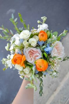 a bridal bouquet with orange, white and blue flowers