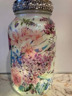 a glass jar with flowers painted on it