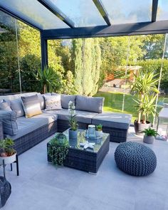 an outdoor living area with couches, tables and potted plants on the patio