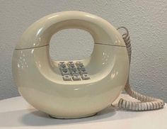 an old fashioned phone sitting on top of a white table next to a gray wall