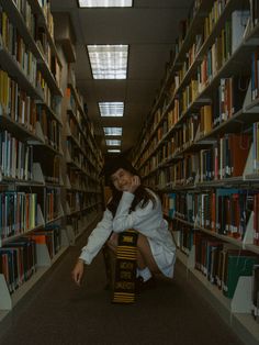 a woman kneeling down in front of a book shelf