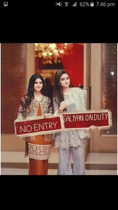 two women standing next to each other holding signs that read no entry and say no entry