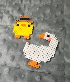 two pieces of perler bead art sitting on a bed with a gray blanket