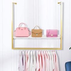 a rack with handbags and purses on it in front of a white wall