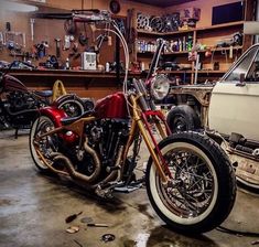 two motorcycles are parked in a garage with other vehicles behind them and one motorcycle is being worked on