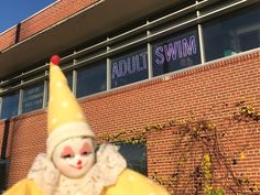 there is a clown statue in front of the building that says adult swim on it