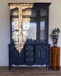 an old china cabinet painted in blue and gold with black paint on the doors, drawers and shelves